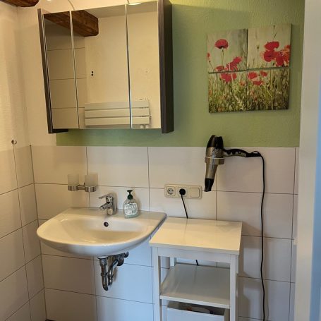 Helles Badezimmer mit Dusche, Waschbecken und modernen Fliesen.
