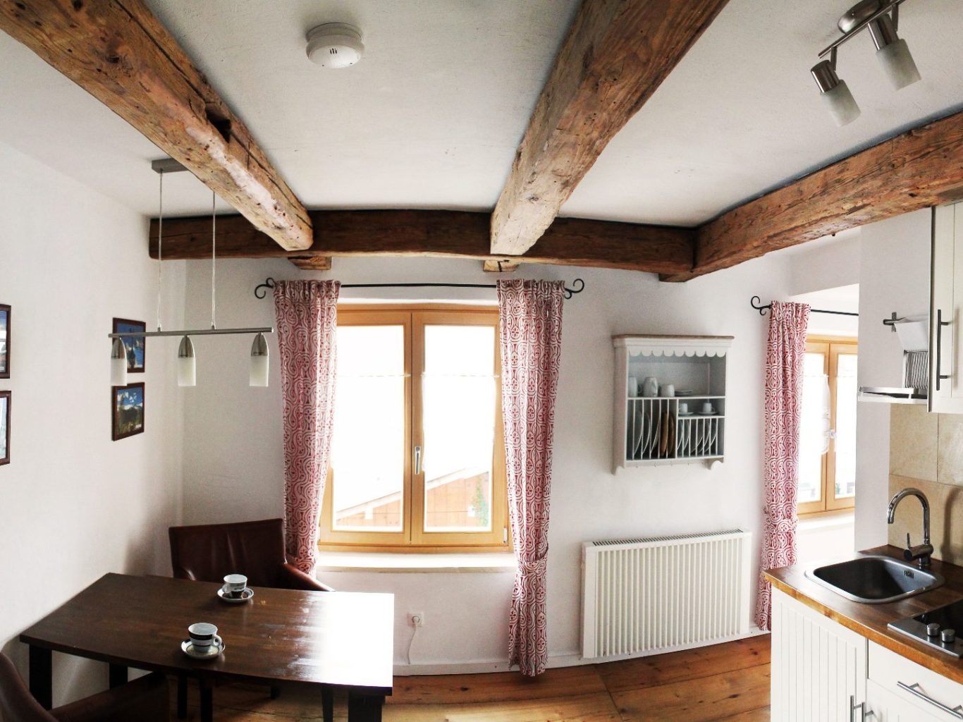 Küche mit Essbereich, Holzdecke und Fenstern, die Tageslicht hereinlassen.