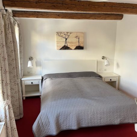 Schlafzimmer mit einem Doppelbett, Nachttischen und Kunstwerken an der Wand.