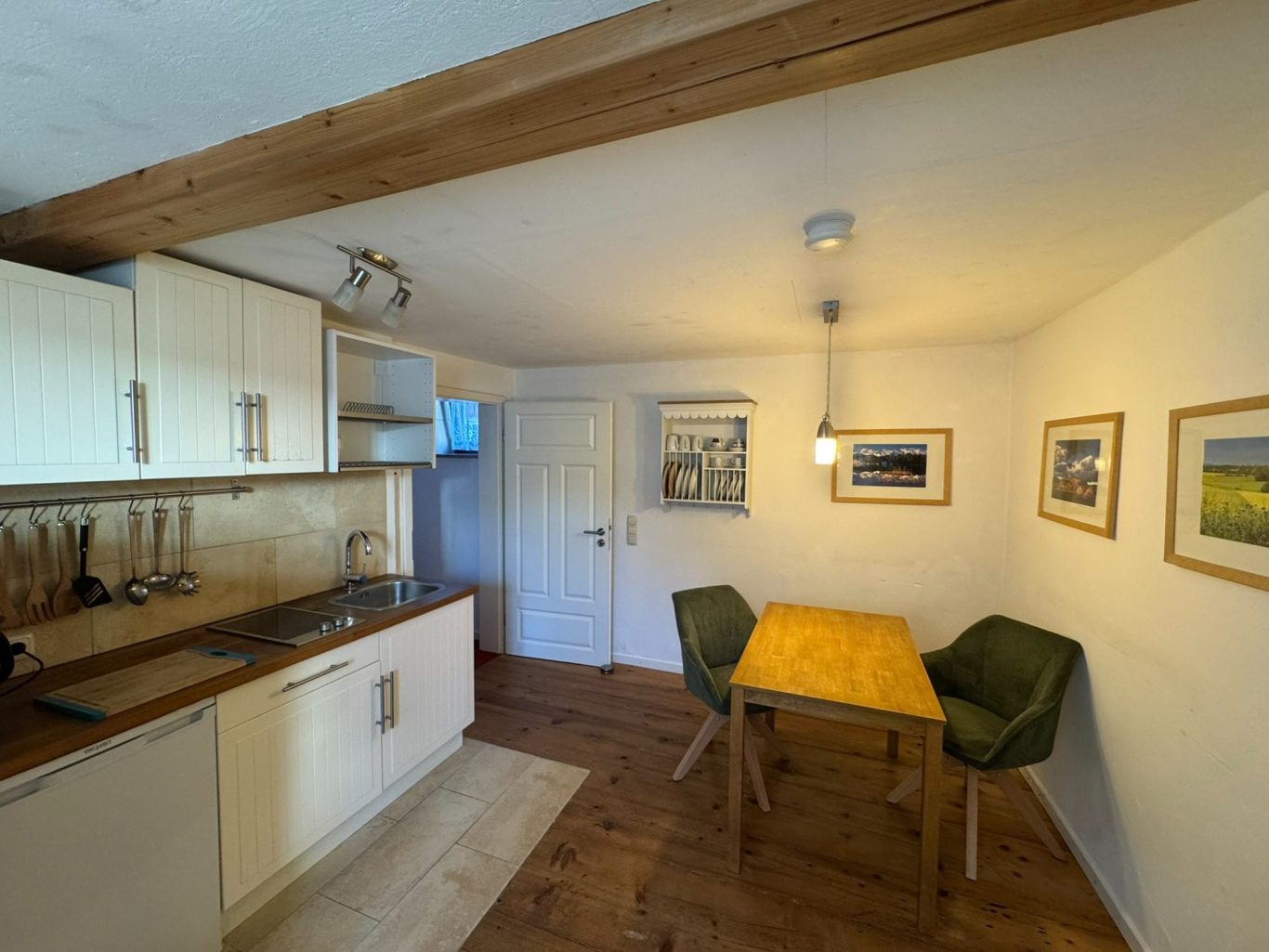 Helle Küche mit Esstisch, grünen Stühlen und Bildern an der Wand.