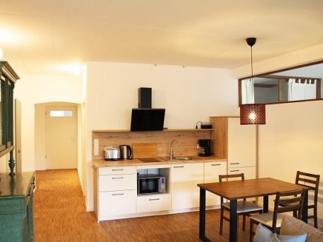 Moderne Küche mit Holzdetails, Essecke und Geräten, helles und geräumiges Ambiente.